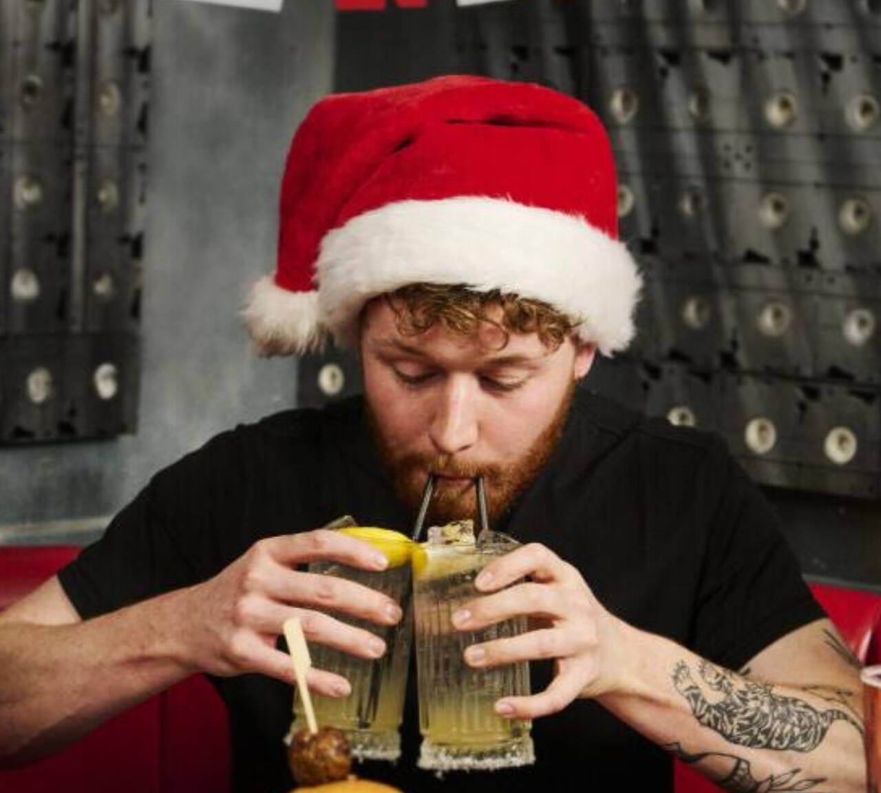 Man wearing Santa hat drinking cocktails